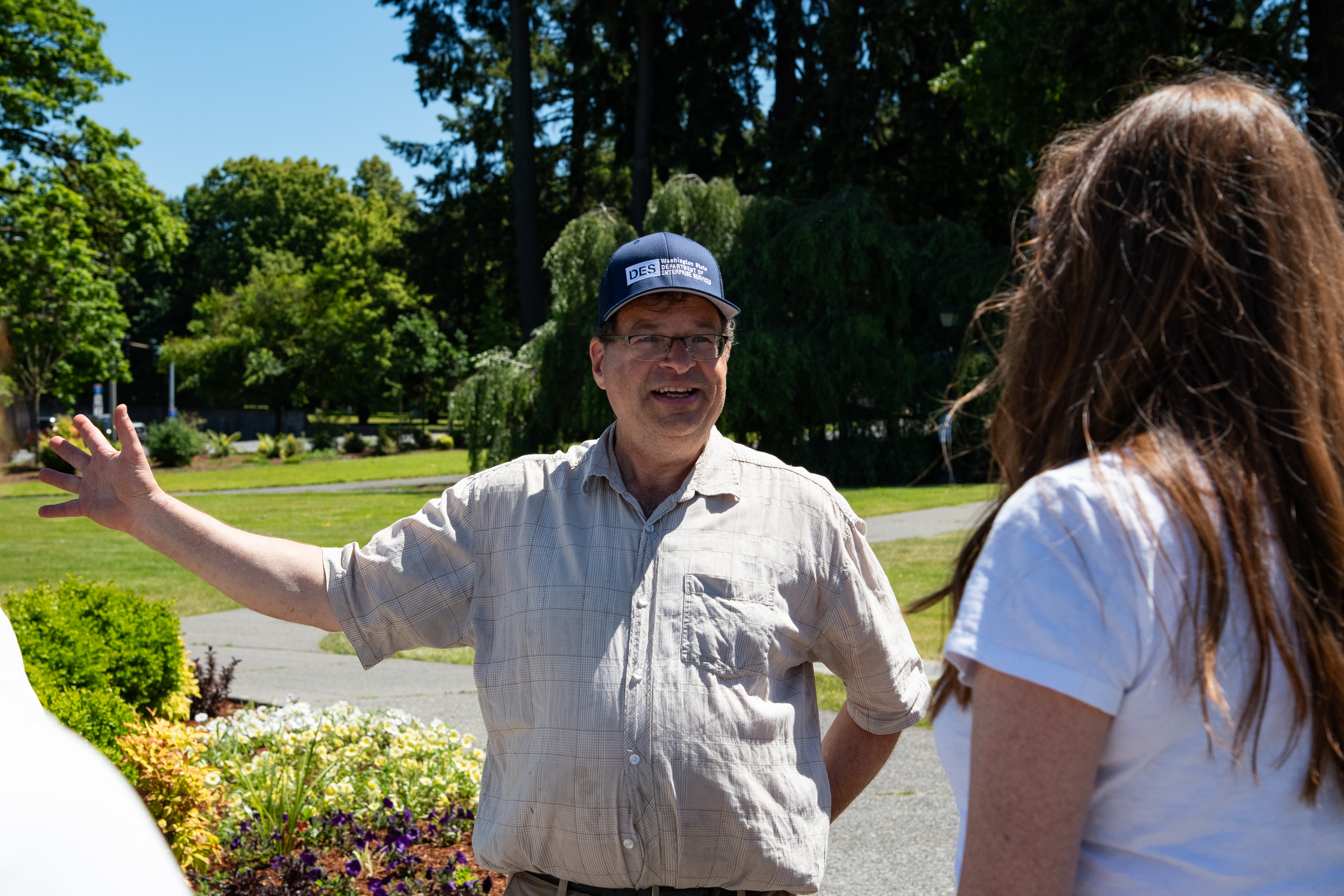 A man wearing a Department of Enterprise Services hat smiles as he shows a woman the Capitol Campus grounds.