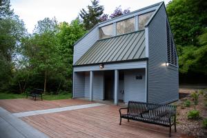 An outdoor scene with two metal park benches set on a wooden deck that leads to a new-looking wooden building (the Interpretive Center restrooms).