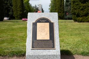 The newly installed Olmsted Legacy Marker, which is a black and bronze plaque on a whiteish gray granite pedestal.