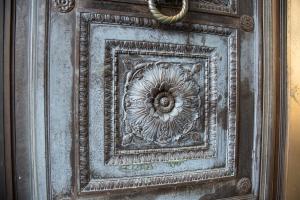 An intricate framed flower design carved into the lower portion of a bronze door.