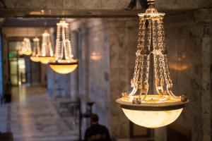 A row of hanging lights in a marble hallway. The lights are suspended by small chains and glow from bowl-shaped glass casings.