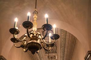 A bronze chandelier hanging in a hallway with lights that imitate candles.