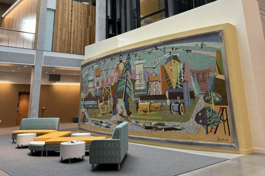 Yellow and blue chairs placed in front of a large glass and stone mosaic mural.