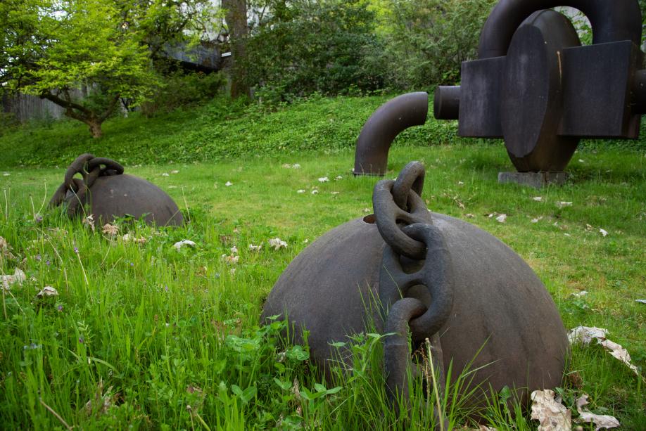 Two metal spheres with chains attached to them buried halfway in grass.