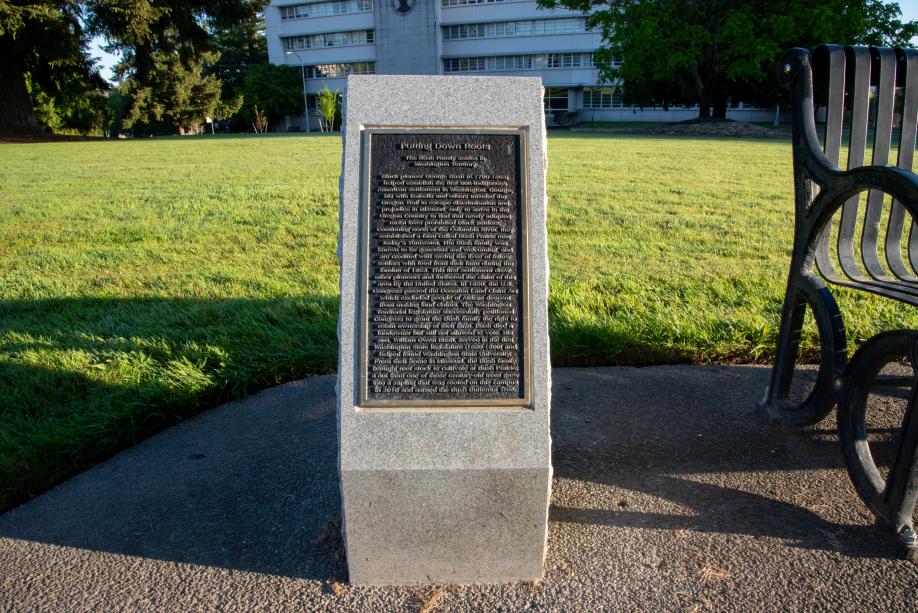 The George Bush Monument next to a metal park bench with an open lawn in the background.