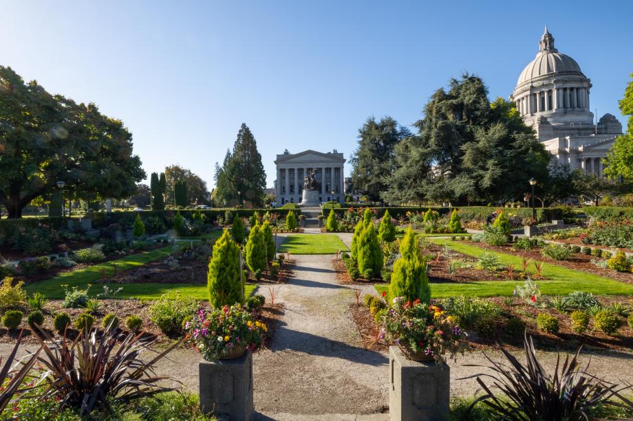 A wide shot of the Sunken Garden, which features various types of flowers, small trees, and bushes, as well as gravel pathways and park benches.