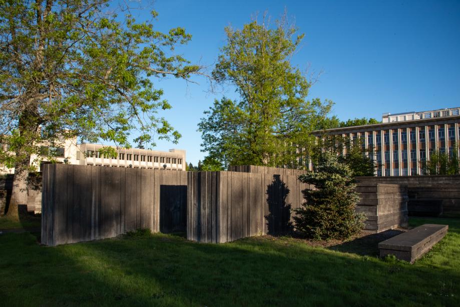 An outdoor scene with the Water Garden's concrete walls surrounded by grass, tall trees, and office buildings.