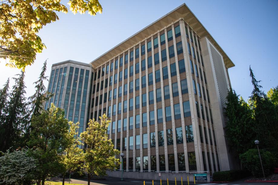 A view of the Highways-Licenses Building from the northwest. This side of the building shows seven stories, and it stands tall above the green and yellow trees surrounding it.