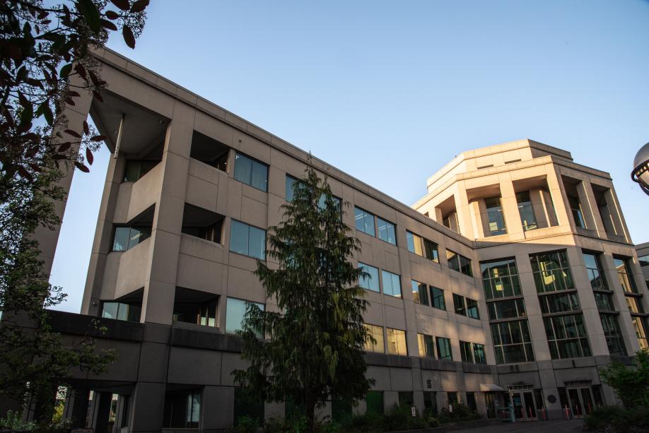 The entrance of the Natural Resources Building, which is located on its southwestern side. This side of the building has four stories, consists of various geometrical shapes, and is lined with various green trees.