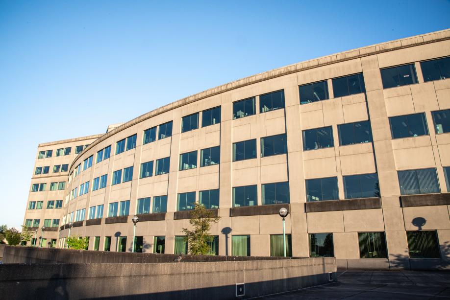 A view of the back side of the Natural Resources Building from the northwest. This side of the building consists of a long, curved wall with three tiers of windows overlooking the Natural Resources Building employee parking lot.