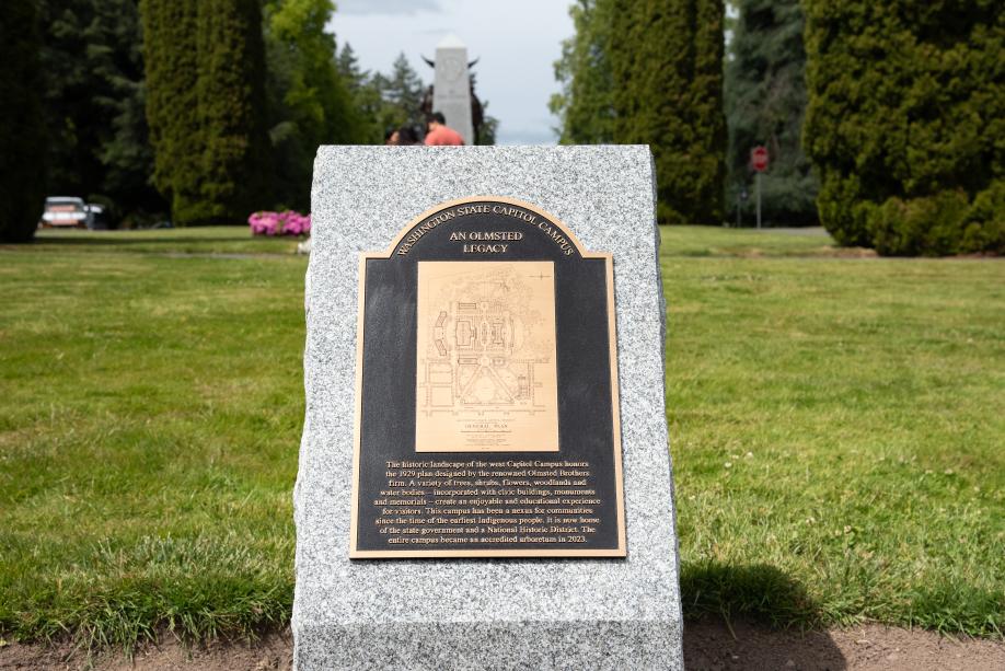 The newly installed Olmsted Legacy Marker, which is a black and bronze plaque on a whiteish gray granite pedestal.