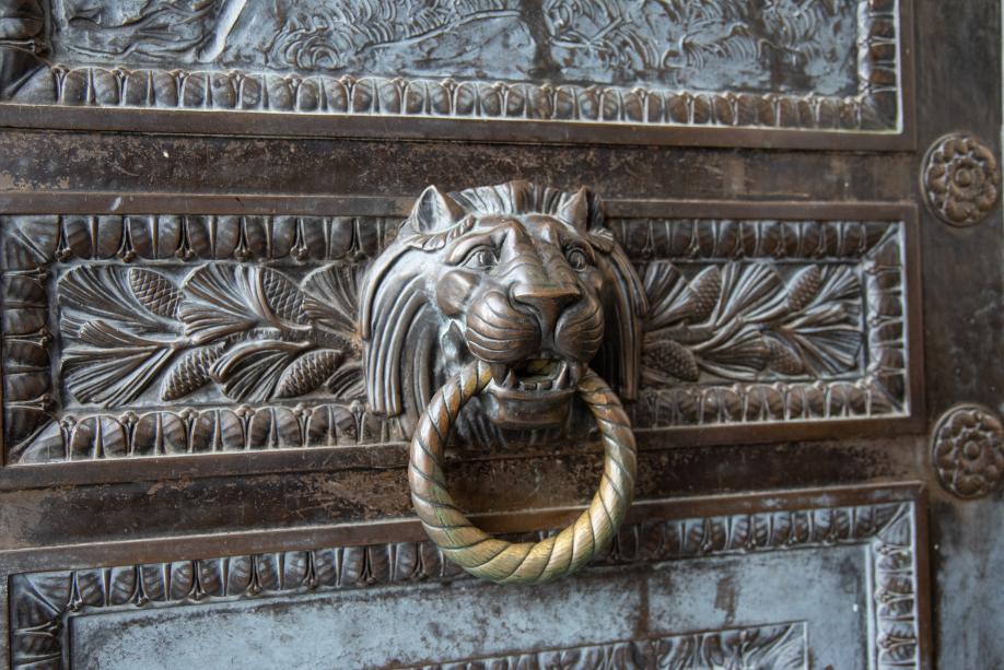 A bronze lion head with a ring in its mouth, which acts as a door handle.