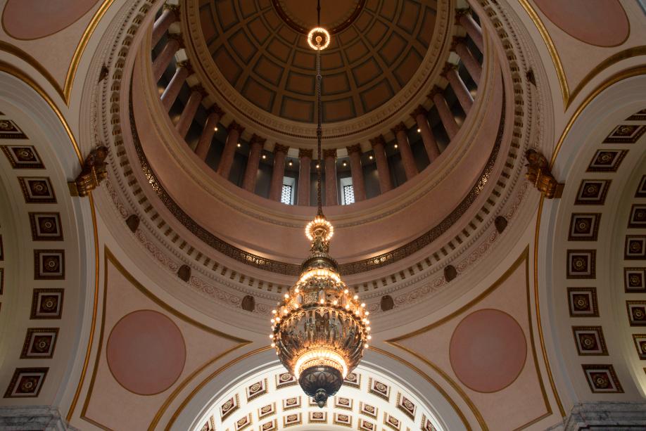 A wide, low angle shot of a giant chandelier hanging from the Legislative Building rotunda. The top of the dome ceiling is visible.