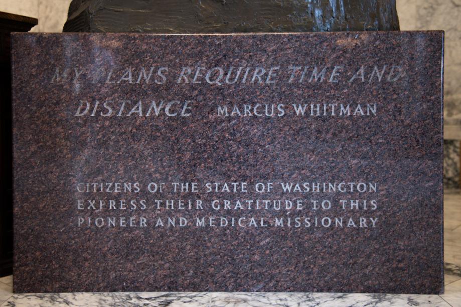 A rectangular, reddish granite based inscribed with text honoring Marcus Whitman.
