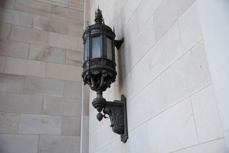 A large bronze lantern hanging on a sandstone wall just outside the north entrance of the Legislative Building.