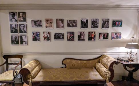 The hallway inside of the Governor's Mansion where portraits of past Governors are hung on a white wall.