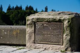 A close-up of one of the Arc of Statehood plaques, titled "Pacific County," with trees in the far distance.