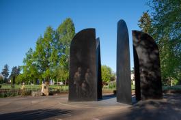 Four large bronze blades inscribed with names and silhouettes of soldiers make up the main portion of the World War II Memorial, which is surrounded by trees and flowers.