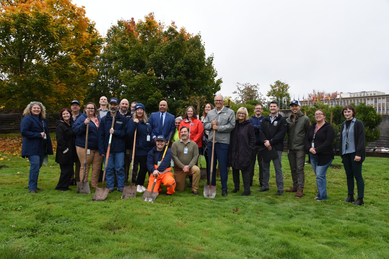 Gov. Jay Inslee, First Spouse Trudi Inslee, community volunteers, and state employees posing with shovels on a lawn on Capitol Campus.