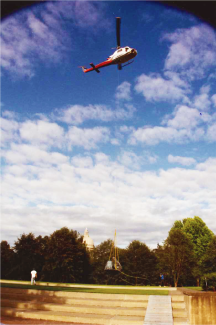 A photo of a helicopter carrying the bronze sculpture into place.