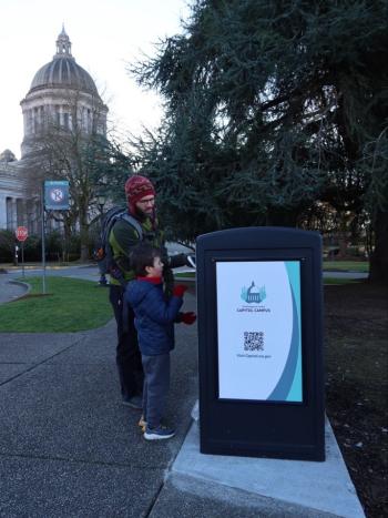 A photo of two people using one of the state Capitol’s new waste bins.