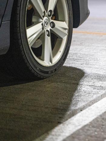 A close up of a car tire next to a painted white line. The car is parked in the Plaza Garage on Capitol Campus in Olympia. ​