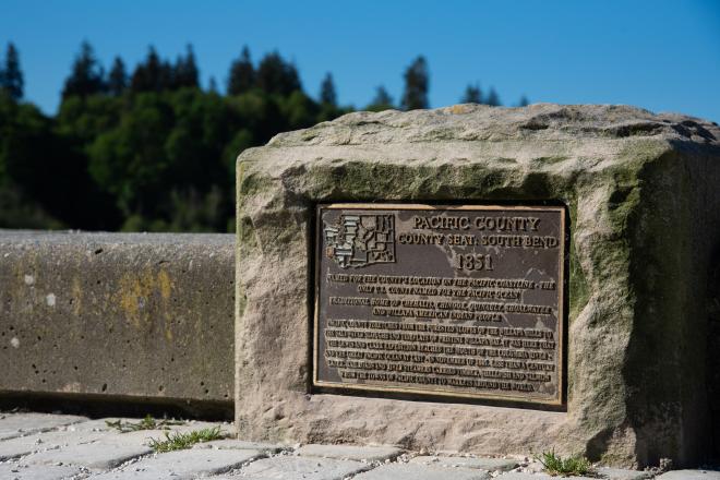 A close-up image of one of the Arc of Statehood plaques with trees in the background.