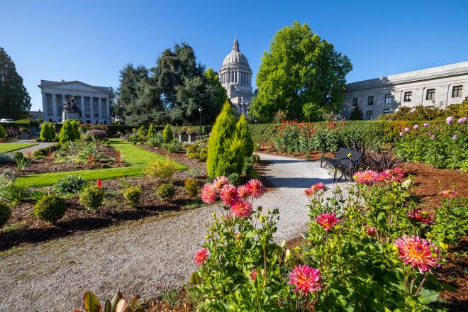 The Sunken Garden path surrounded by vibrant trees and flowers, with the Legislative Building in the background.