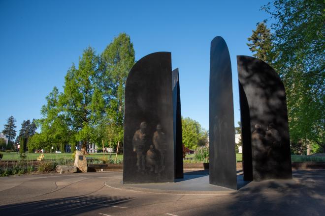 A wide shot of the World War II Memorial's bronze blades with a plaque and trees in the background.