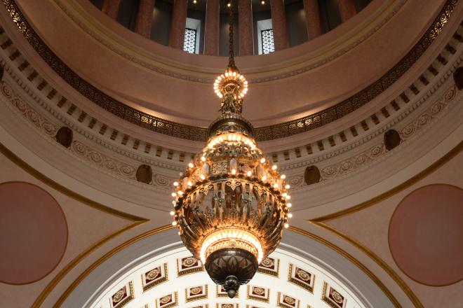 A wide, low angle shot of a giant chandelier hanging from the Legislative Building rotunda.